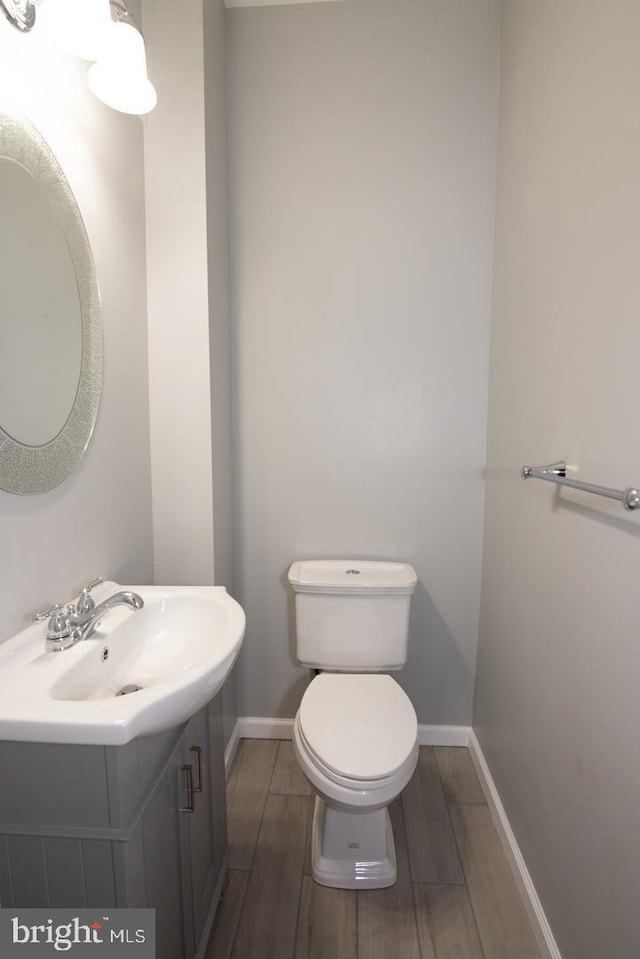 bathroom with vanity, toilet, and wood-type flooring