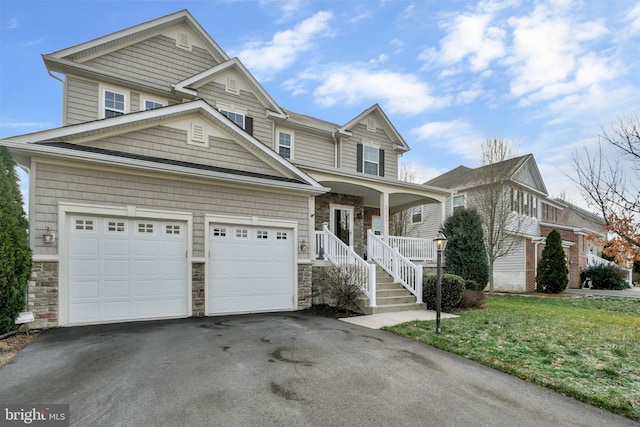 view of front of property with a porch, a garage, and a front lawn