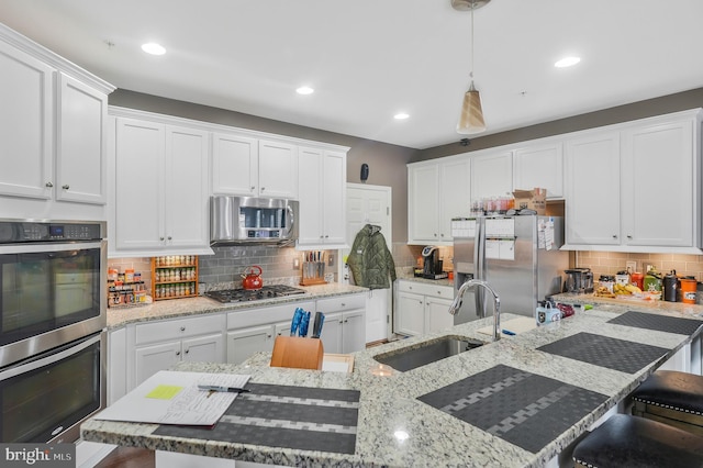 kitchen with pendant lighting, white cabinets, sink, a breakfast bar area, and stainless steel appliances