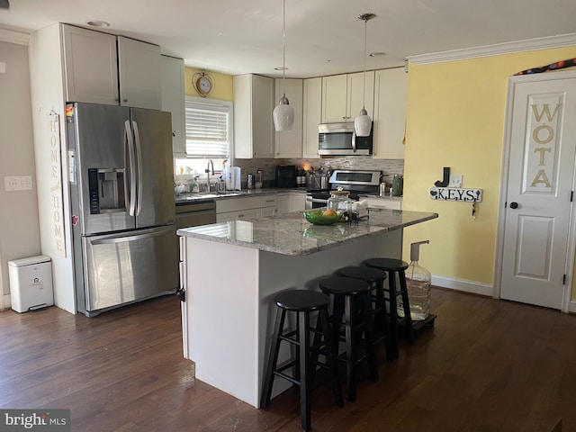 kitchen with stainless steel appliances, light stone counters, decorative light fixtures, decorative backsplash, and a kitchen island