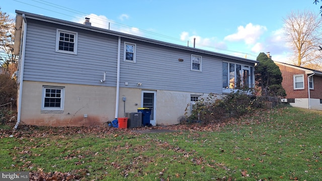 back of house featuring central air condition unit and a yard