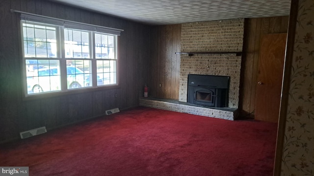 carpeted living room with a fireplace, wood walls, and a textured ceiling