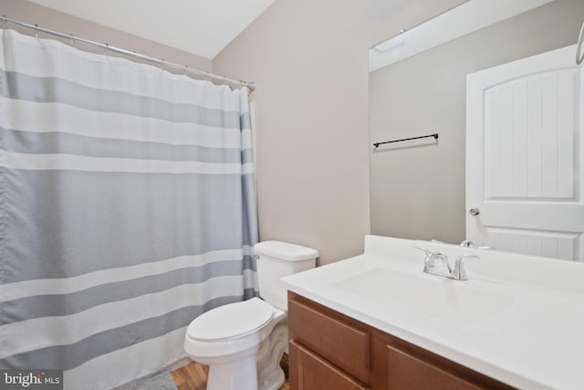 bathroom featuring hardwood / wood-style floors, vanity, toilet, and lofted ceiling