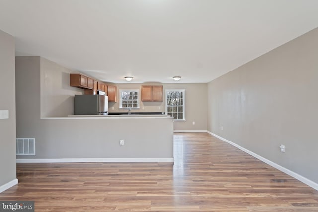 kitchen featuring stainless steel refrigerator, sink, and light wood-type flooring