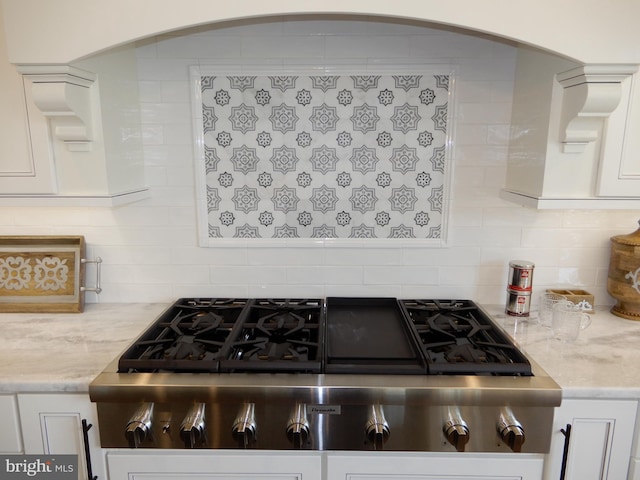 kitchen featuring white cabinets, decorative backsplash, light stone countertops, and stainless steel gas stovetop