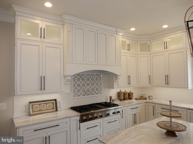 kitchen featuring white cabinets, decorative backsplash, light stone countertops, and stainless steel gas cooktop