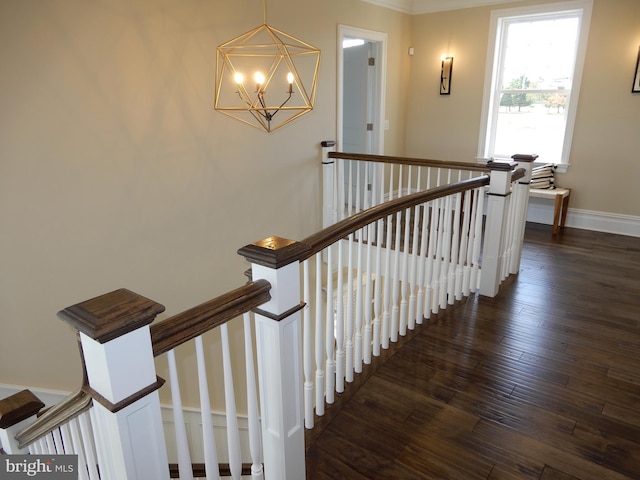 staircase with hardwood / wood-style floors, crown molding, and an inviting chandelier