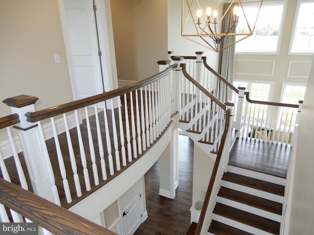 stairs with hardwood / wood-style flooring and a notable chandelier