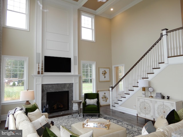 living room with crown molding, dark hardwood / wood-style flooring, a high end fireplace, and a high ceiling