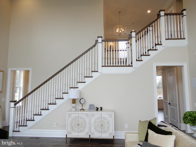 stairway featuring hardwood / wood-style flooring, a notable chandelier, and a high ceiling