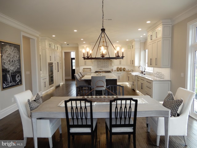 dining area with a chandelier, sink, dark wood-type flooring, and ornamental molding