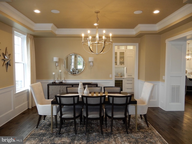 dining area featuring a raised ceiling, beverage cooler, dark wood-type flooring, crown molding, and a notable chandelier