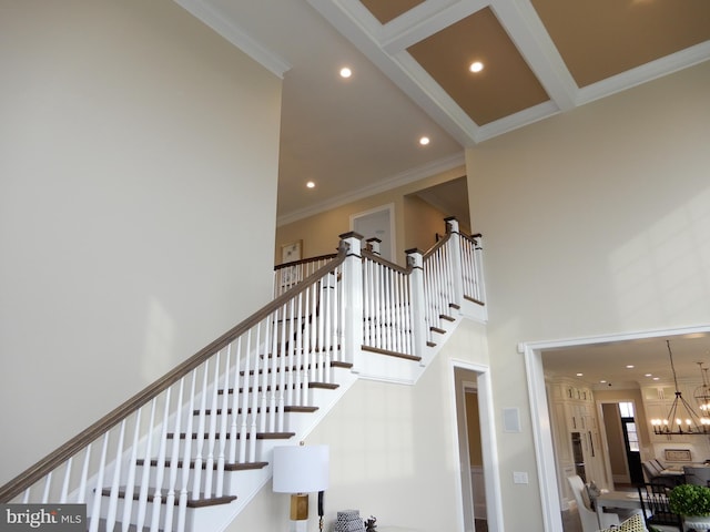 stairway featuring beamed ceiling, a towering ceiling, crown molding, and an inviting chandelier