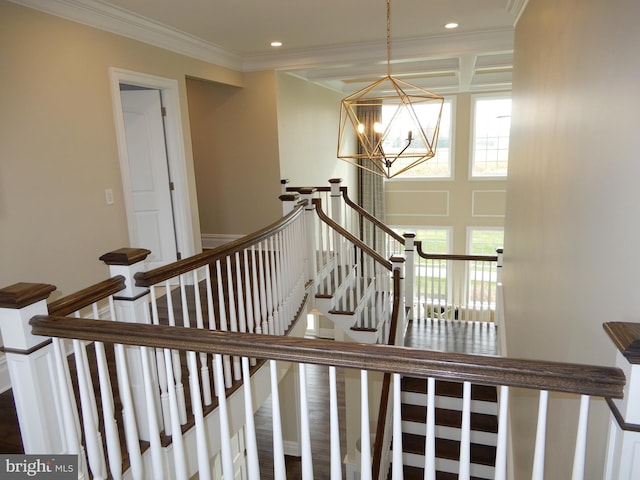 stairway with hardwood / wood-style floors, ornamental molding, and an inviting chandelier