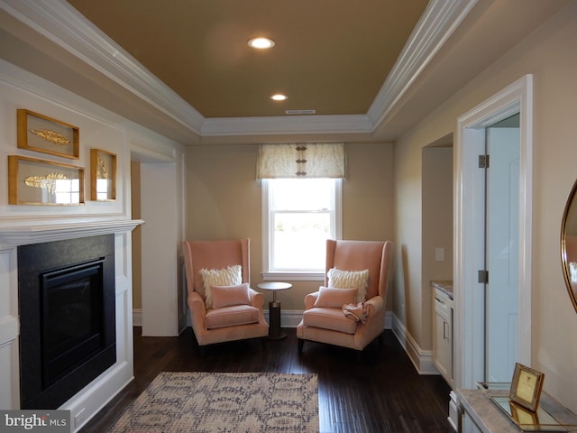 sitting room with a raised ceiling, dark wood-type flooring, and ornamental molding