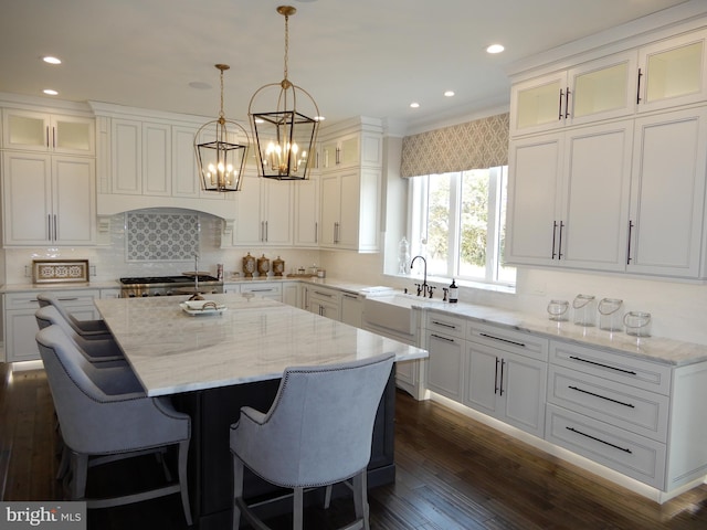 kitchen featuring light stone counters, sink, an island with sink, and decorative light fixtures