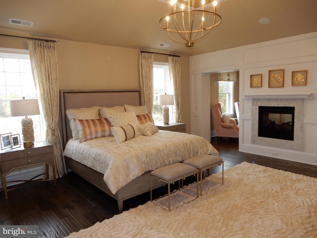 bedroom with a multi sided fireplace, dark hardwood / wood-style flooring, and a chandelier