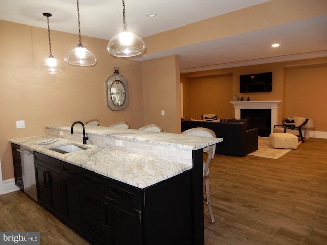 kitchen featuring sink, hanging light fixtures, a kitchen breakfast bar, dark hardwood / wood-style flooring, and stainless steel dishwasher