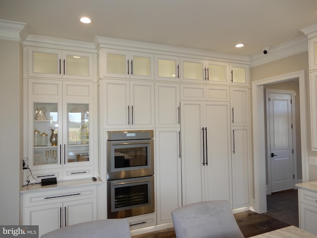 kitchen with white cabinetry, stainless steel double oven, and ornamental molding