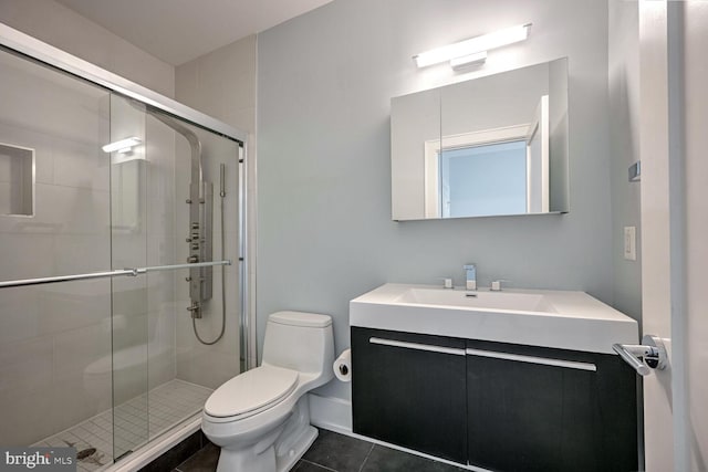 bathroom with tile patterned flooring, vanity, a shower with shower door, and toilet