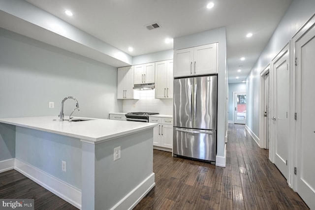 kitchen featuring sink, backsplash, kitchen peninsula, white cabinets, and appliances with stainless steel finishes