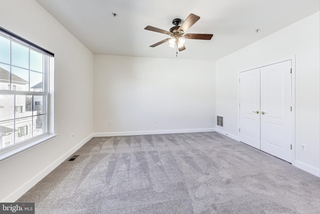 unfurnished bedroom featuring ceiling fan, light carpet, and a closet