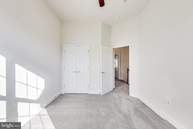 unfurnished bedroom with ceiling fan, light colored carpet, high vaulted ceiling, and a closet