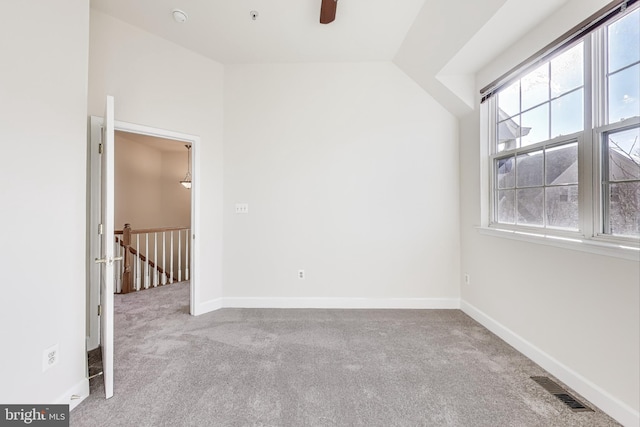 unfurnished room featuring light colored carpet, vaulted ceiling, plenty of natural light, and ceiling fan