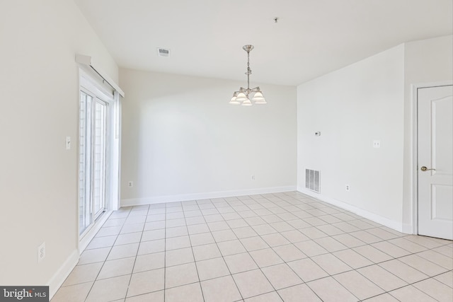 tiled spare room featuring an inviting chandelier