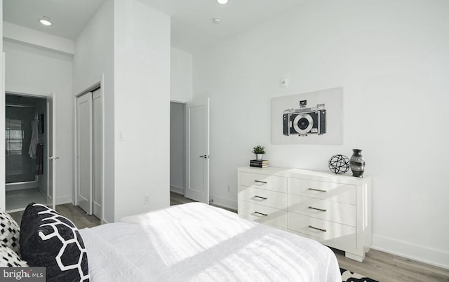 bedroom with a towering ceiling, light hardwood / wood-style flooring, and a closet