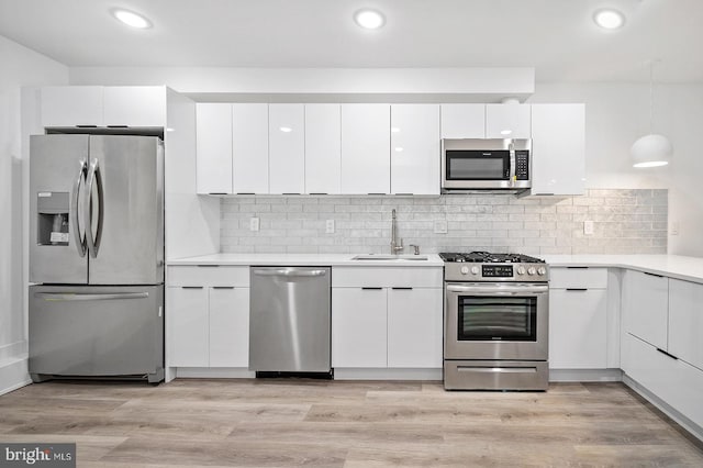 kitchen featuring sink, stainless steel appliances, decorative light fixtures, decorative backsplash, and white cabinets