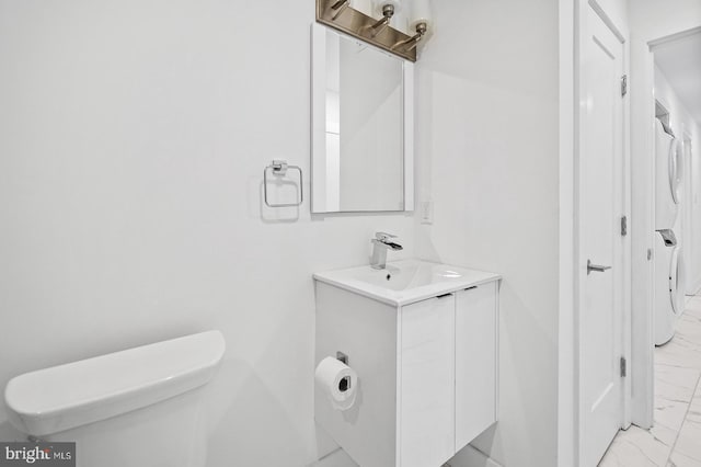 bathroom with vanity, stacked washer and clothes dryer, and toilet