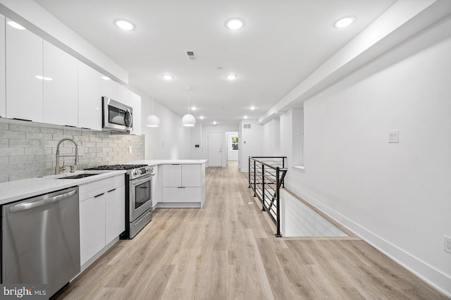 kitchen with white cabinets, appliances with stainless steel finishes, decorative backsplash, and pendant lighting