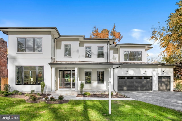 view of front of home with covered porch, a garage, and a front yard