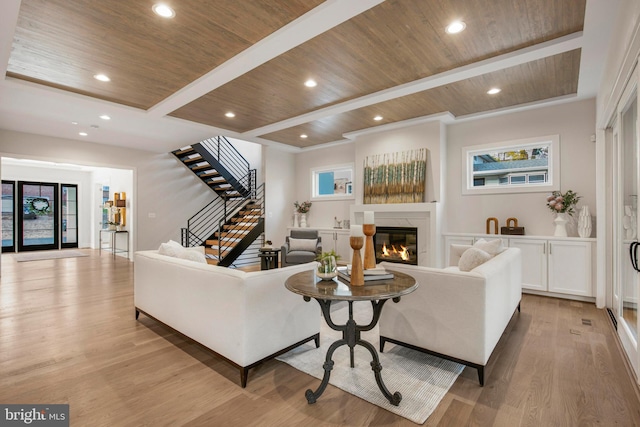 living room with a high end fireplace, wood ceiling, a healthy amount of sunlight, beam ceiling, and light hardwood / wood-style flooring