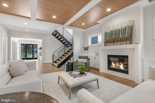 living room featuring light hardwood / wood-style floors, wooden ceiling, a wealth of natural light, and a premium fireplace