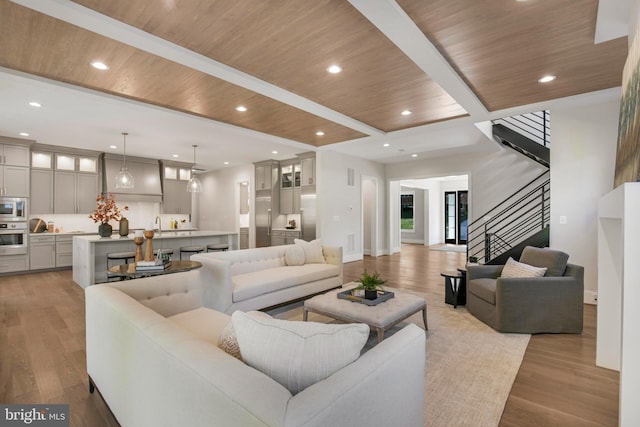 living room featuring beamed ceiling, light hardwood / wood-style floors, and wooden ceiling