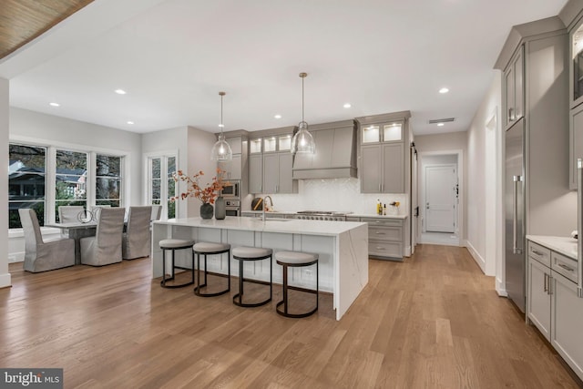 kitchen with premium range hood, gray cabinetry, sink, and pendant lighting