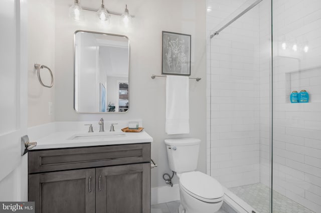 bathroom featuring a tile shower, vanity, and toilet