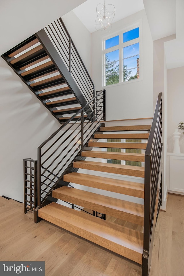 staircase featuring hardwood / wood-style flooring and an inviting chandelier