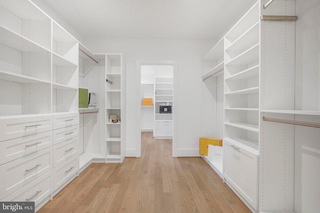 walk in closet with light hardwood / wood-style floors