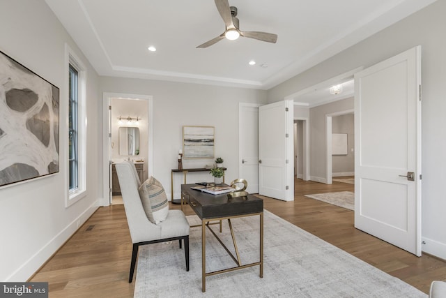 office area featuring ceiling fan, a raised ceiling, and light hardwood / wood-style flooring