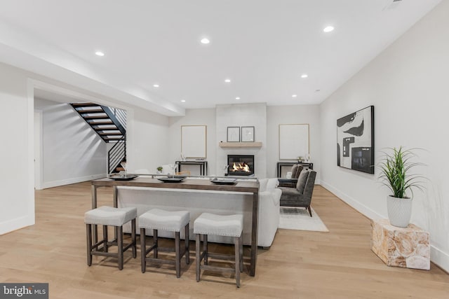 bar with a fireplace and light hardwood / wood-style flooring