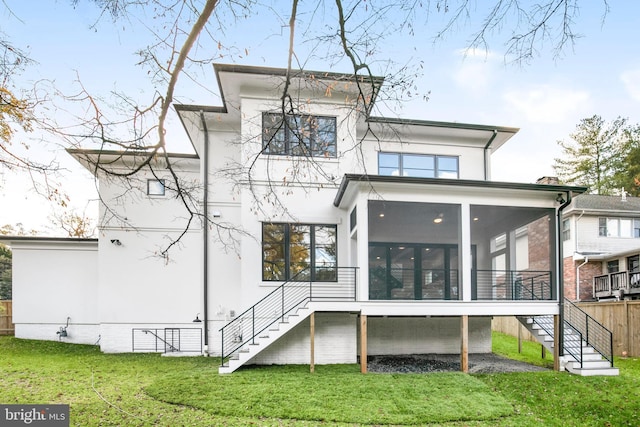 rear view of property featuring a lawn and a sunroom