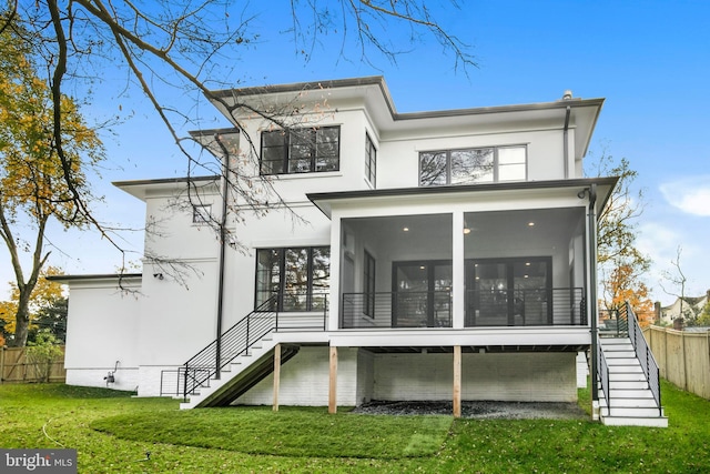 rear view of house featuring a lawn and a sunroom