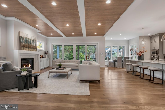 living room with a high end fireplace, beam ceiling, light hardwood / wood-style flooring, and wood ceiling