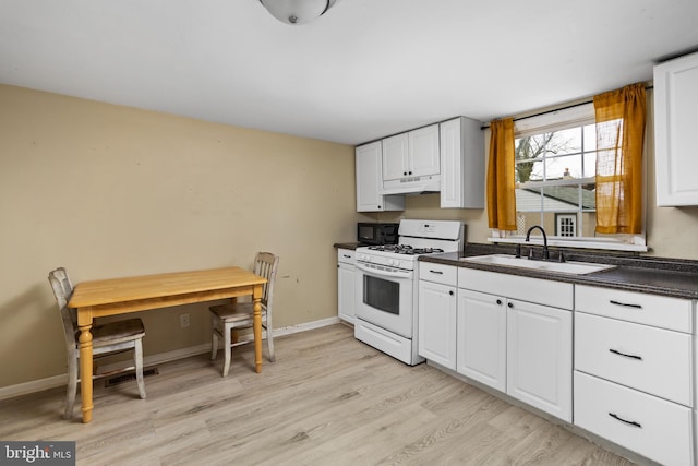 kitchen with white range with gas cooktop, sink, white cabinets, and light hardwood / wood-style flooring