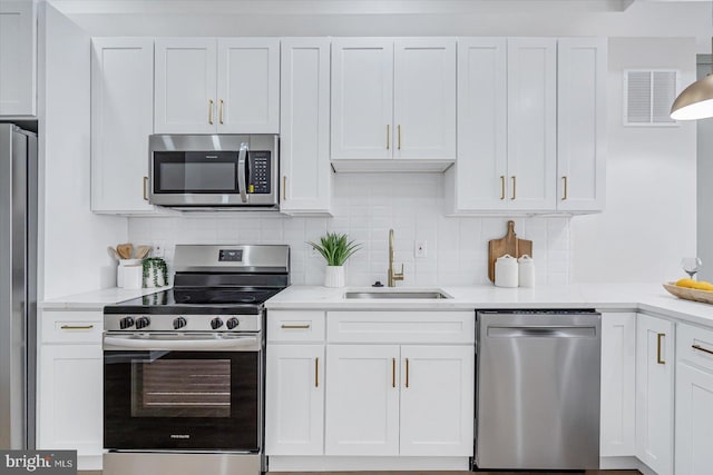 kitchen with tasteful backsplash, white cabinetry, sink, and stainless steel appliances