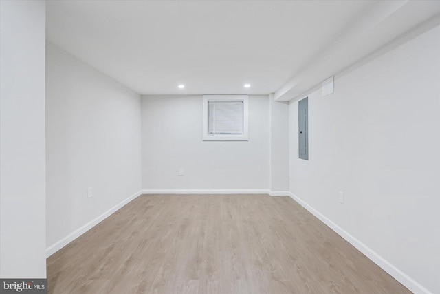 basement featuring electric panel and light hardwood / wood-style flooring