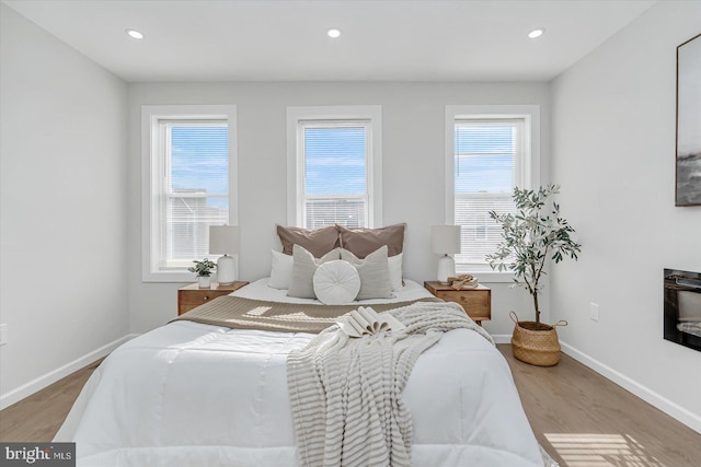 bedroom with hardwood / wood-style floors and multiple windows